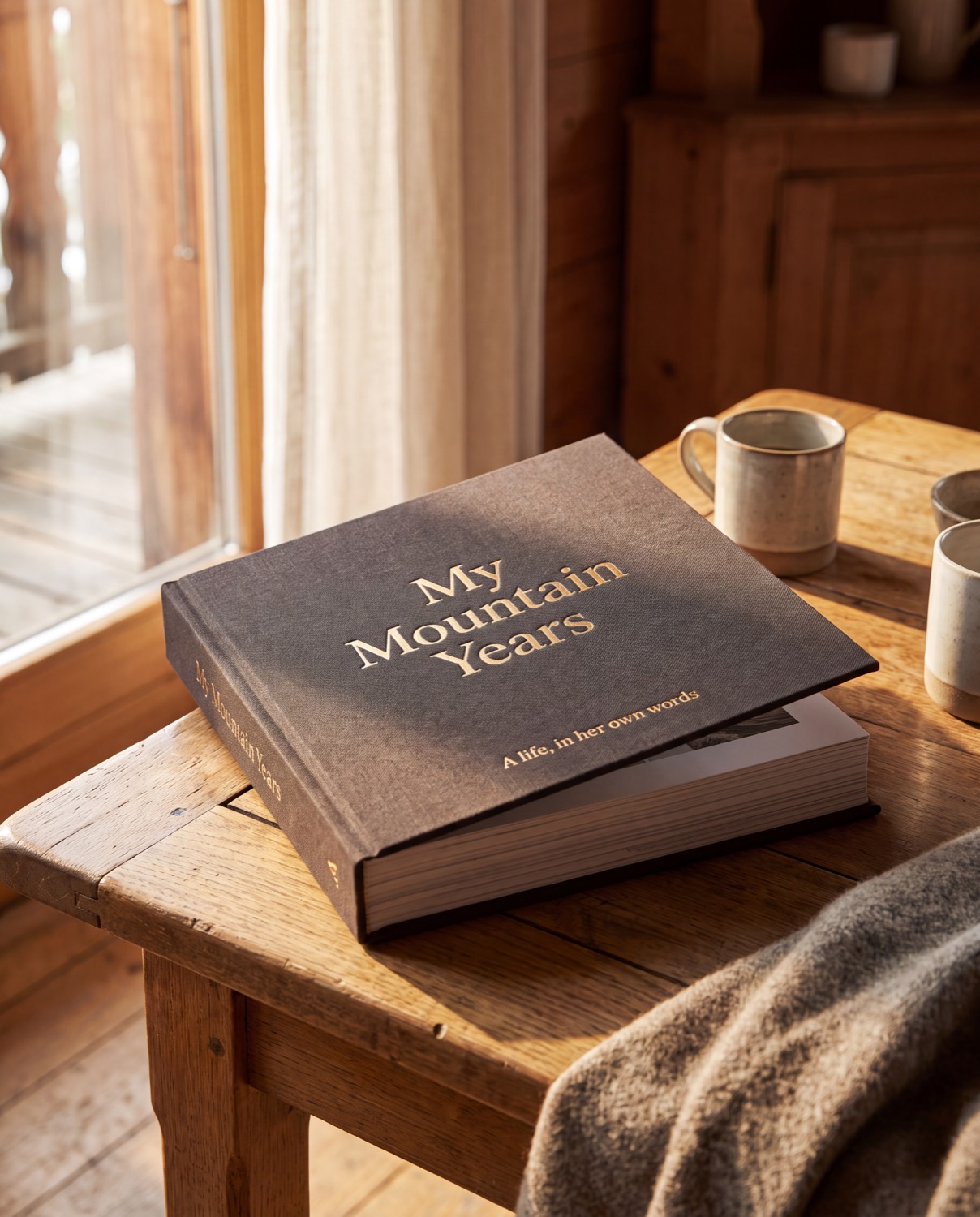 A finished hardcover memoir resting on a wooden stool in warm light.